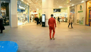 a man in a red tracksuit is walking through a shopping mall