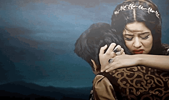a woman wearing a tiara is hugging a man with a ring on her finger
