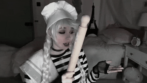 a girl in a chef 's hat holds a rolling pin