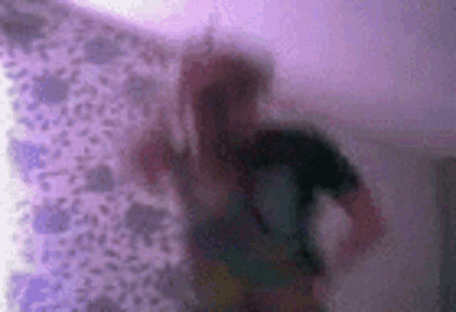 a blurry picture of a person standing in front of a purple background .