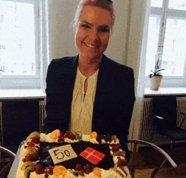 a woman is smiling while holding a cake that has the number 50 on it