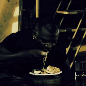 a man is sitting at a table eating a plate of food