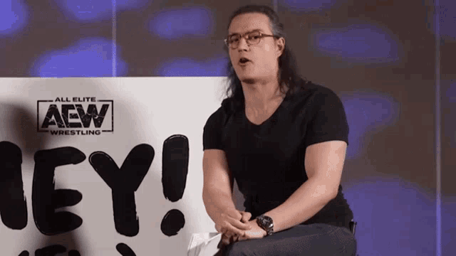 a man is sitting in front of a sign that says hey