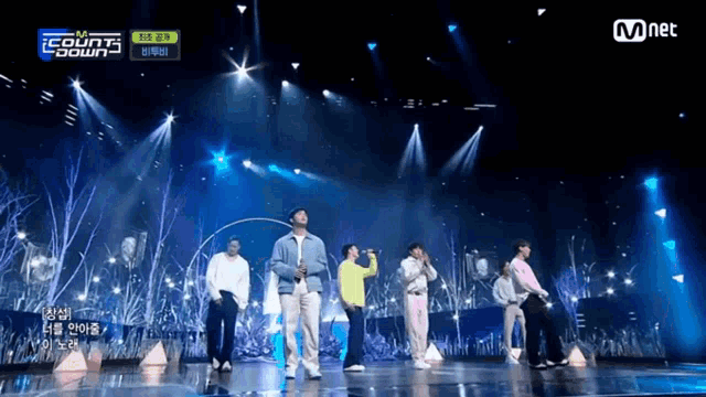 a group of people standing on a stage with a mnet logo on the bottom right