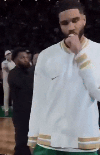 a man wearing a white nike jacket and green pants stands on a basketball court