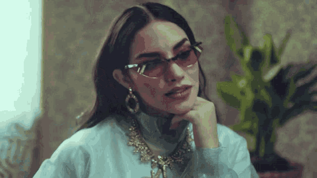 a woman wearing sunglasses and a necklace looks to the side