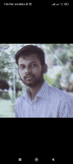 a man in a plaid shirt is looking at the camera with the time of 7:06 pm