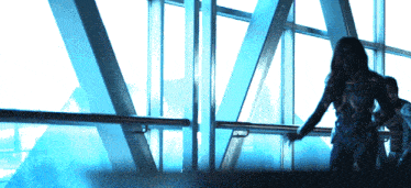 a woman stands in front of a large window