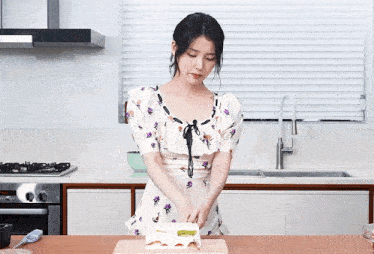 a woman in a floral dress is cutting a cake