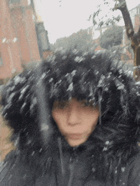 a person wearing a black jacket with a black fur hood