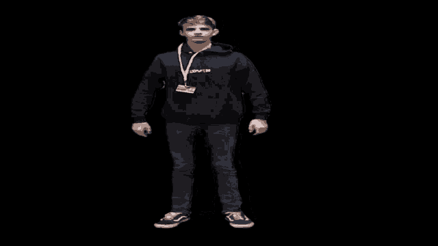 a young man in a black hoodie and jeans is standing in front of a black background