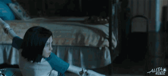 a girl is sitting on the floor in a dark room with the word alita on the bottom right