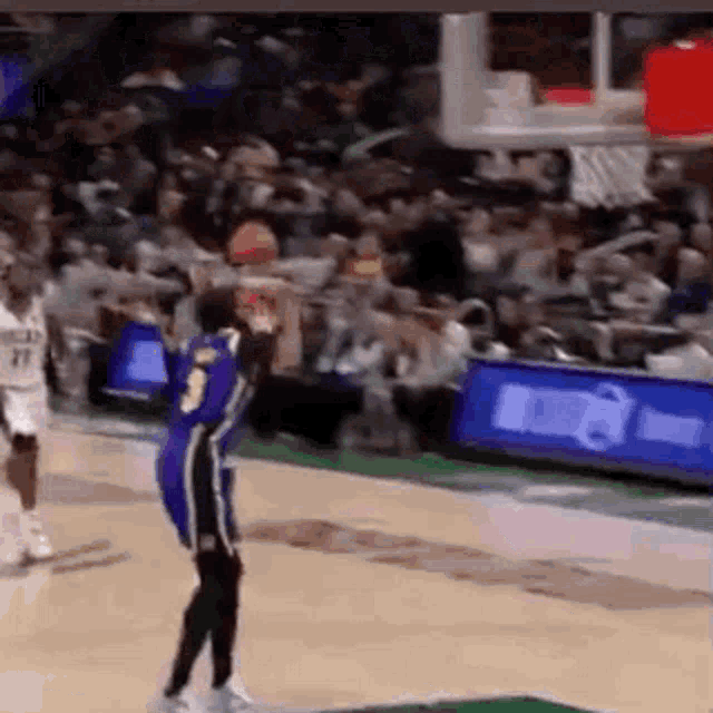a basketball player is jumping in the air to catch a basketball during a basketball game .