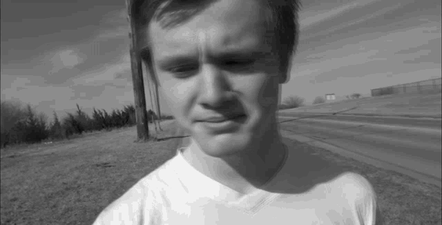a black and white photo of a young man wearing a white t-shirt
