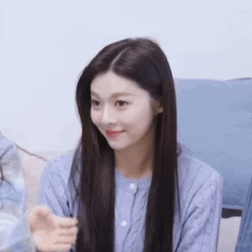 a woman with long hair is wearing a blue sweater and smiling .