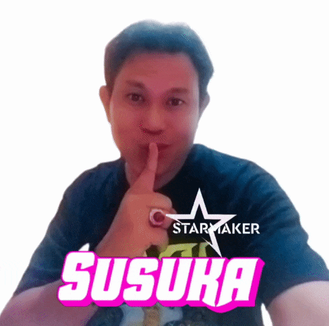 a man is making a shhh gesture with his finger in front of his mouth and the word susuka is on the bottom of his shirt