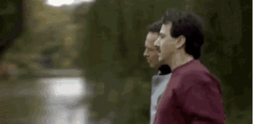 a man in a red shirt is running down a path in the park .