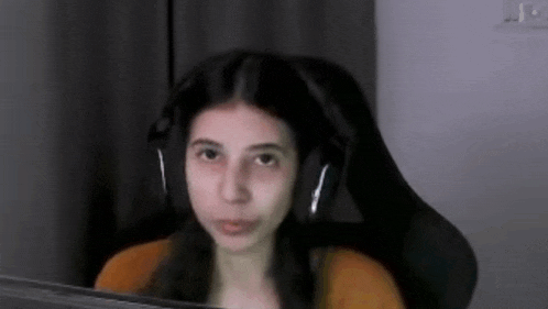 a young girl wearing headphones is sitting in a chair in front of a computer screen .