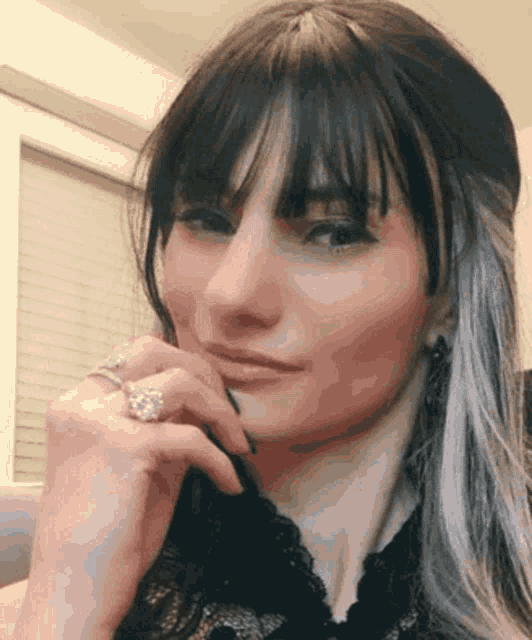 a close up of a woman 's face with a diamond ring on her finger