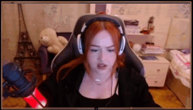 a woman wearing headphones and a black shirt is sitting in a chair