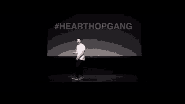 a man is walking on a stage in front of a sign that says hearthopgang .