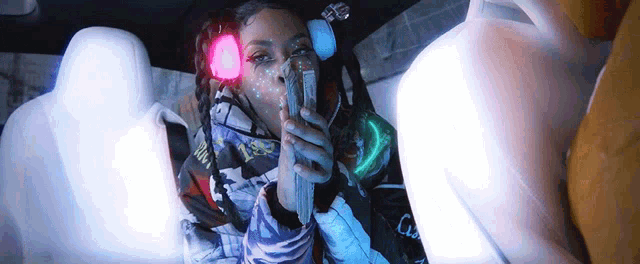 a woman sitting in the back seat of a car smoking a cigarette and wearing headphones with the letter c on them