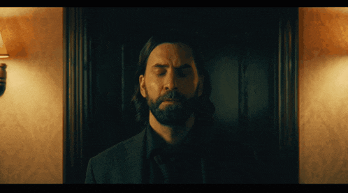 a man with a beard is standing in front of a door with his eyes closed