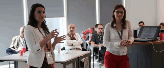 two women are standing in front of a group of people and one has a name tag that says ' a. ' on it