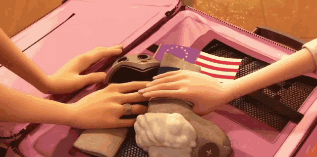 a pink suitcase is filled with clothes and a flag