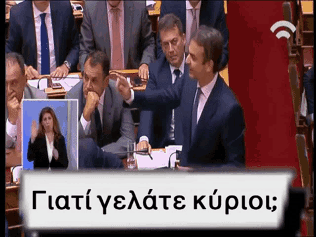 a group of men in suits and ties are sitting in a room with a sign in a foreign language that says ' '