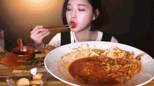a woman is eating a plate of food with chopsticks .