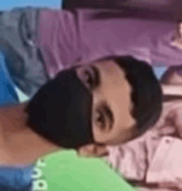 a man wearing a black face mask is laying on a green shirt .