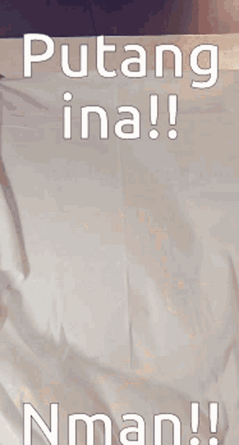 a man is laying on a bed with the words putang ina nman