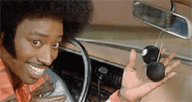 a man is sitting in a car holding a pair of sunglasses in his hand .