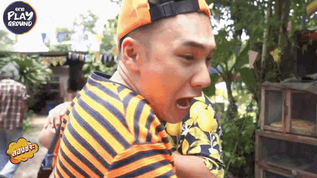 a man wearing an orange hat and an orange and black striped shirt is screaming