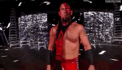 a wrestler without a shirt is standing in front of a crowd .