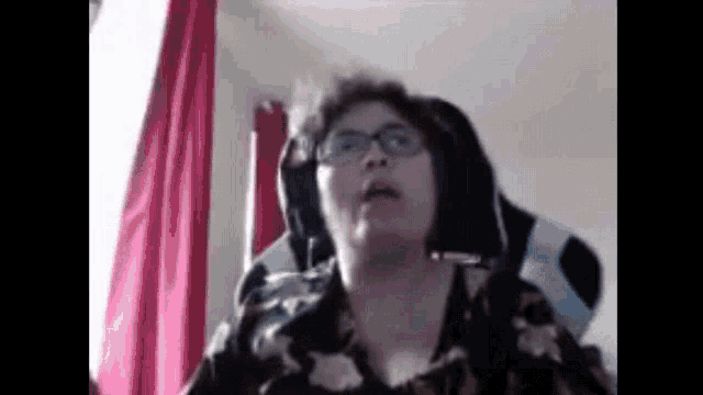 a woman wearing glasses and headphones is sitting in a chair .