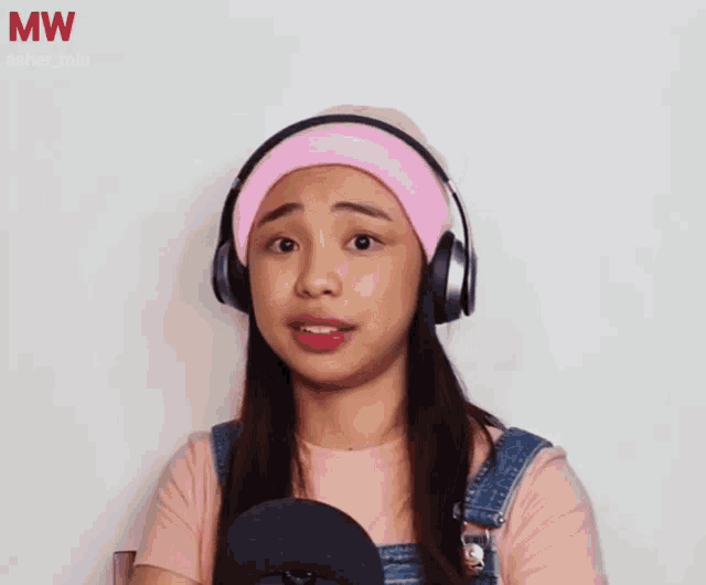 a woman wearing headphones and a pink beanie with mw asher_miu on the bottom