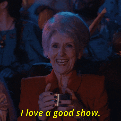 a woman in a red jacket is smiling and holding a cup with the words i love a good show below her