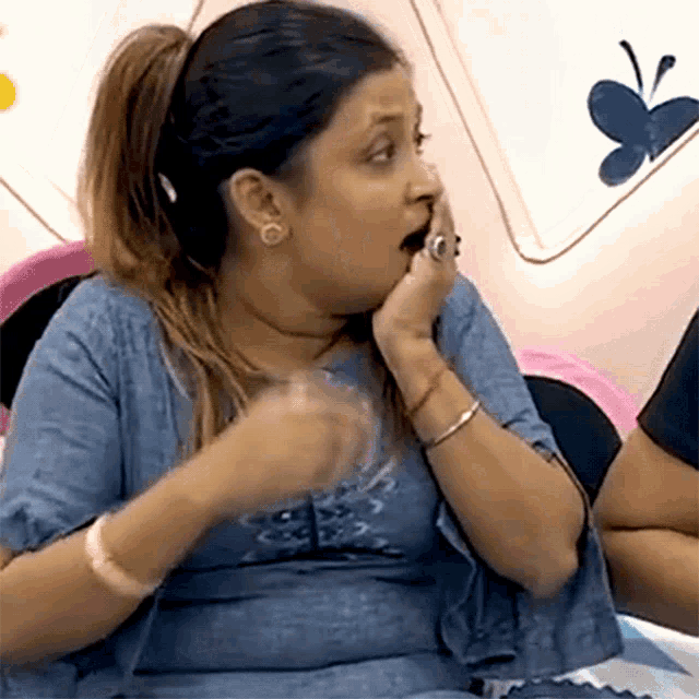 a woman in a blue shirt is making a funny face with her mouth open .