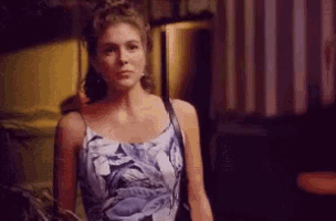 a woman in a blue and white floral dress is standing in a dark room .