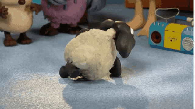 a toy sheep is crawling on the floor in front of a toy radio