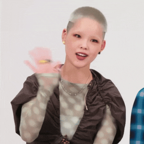 a woman with a shaved head wearing a polka dot top