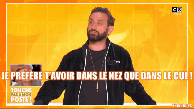 a man with a beard stands in front of a screen that says touche pas a mon poste on it