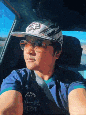 a man wearing a fox hat and sunglasses is driving a car