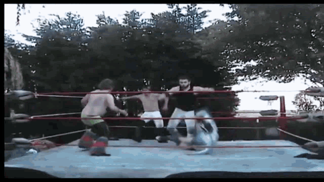 a group of men are wrestling in a ring outside