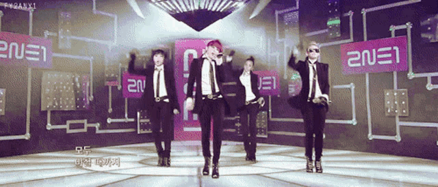 a group of people are dancing in front of a sign that says ' 2ne1 '