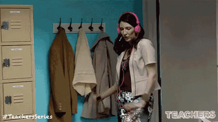 a woman wearing pink headphones is standing in front of a locker .