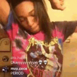 a woman in a pink t-shirt is dancing in a room with her arms outstretched .