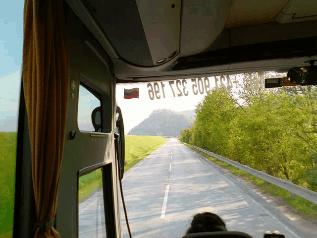 a view of a road from the inside of a bus with a sticker on the windshield that says tsc 302 130